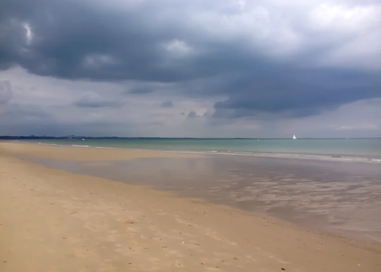 A vast sandy beach under a brooding sky