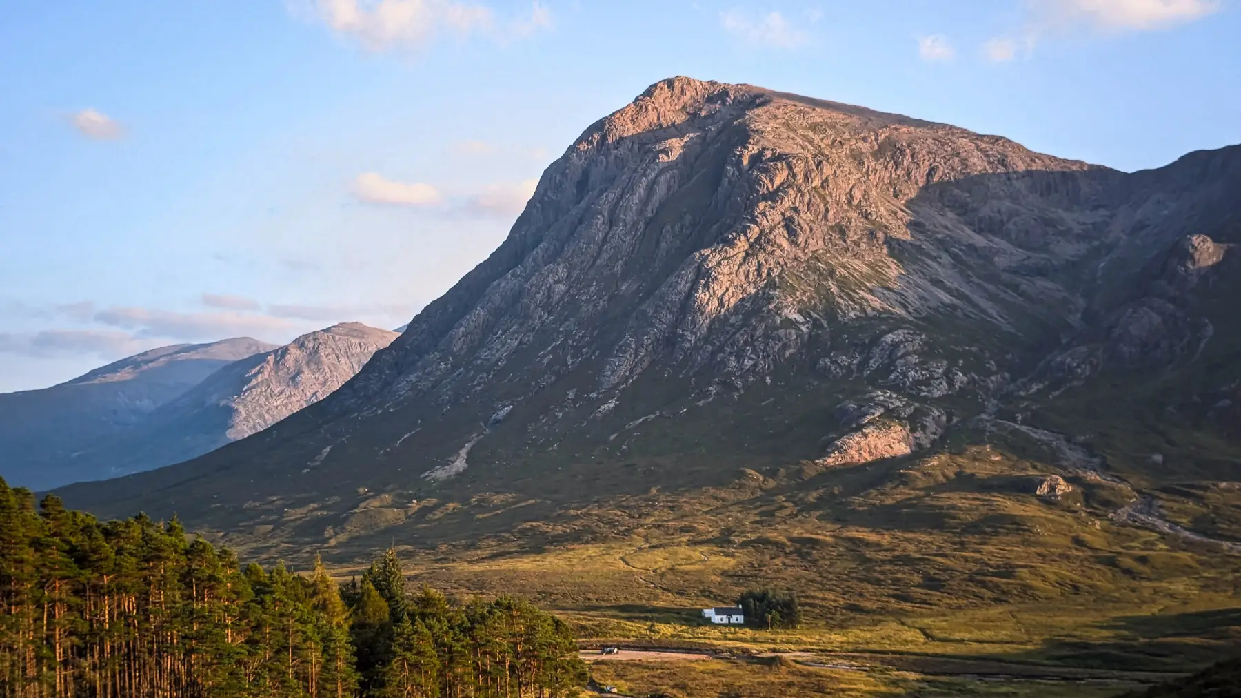 A tiny white climbers' hut is nestled at the bottom of a Buchaille Etive Mor mountain in the Scottish Highlands