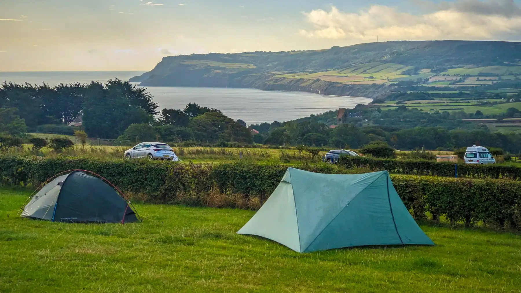 2 backpacking tents pitched on Hooks House Farm campsite on the coast to coast trail. Robin Hood's Bay is in the background.
