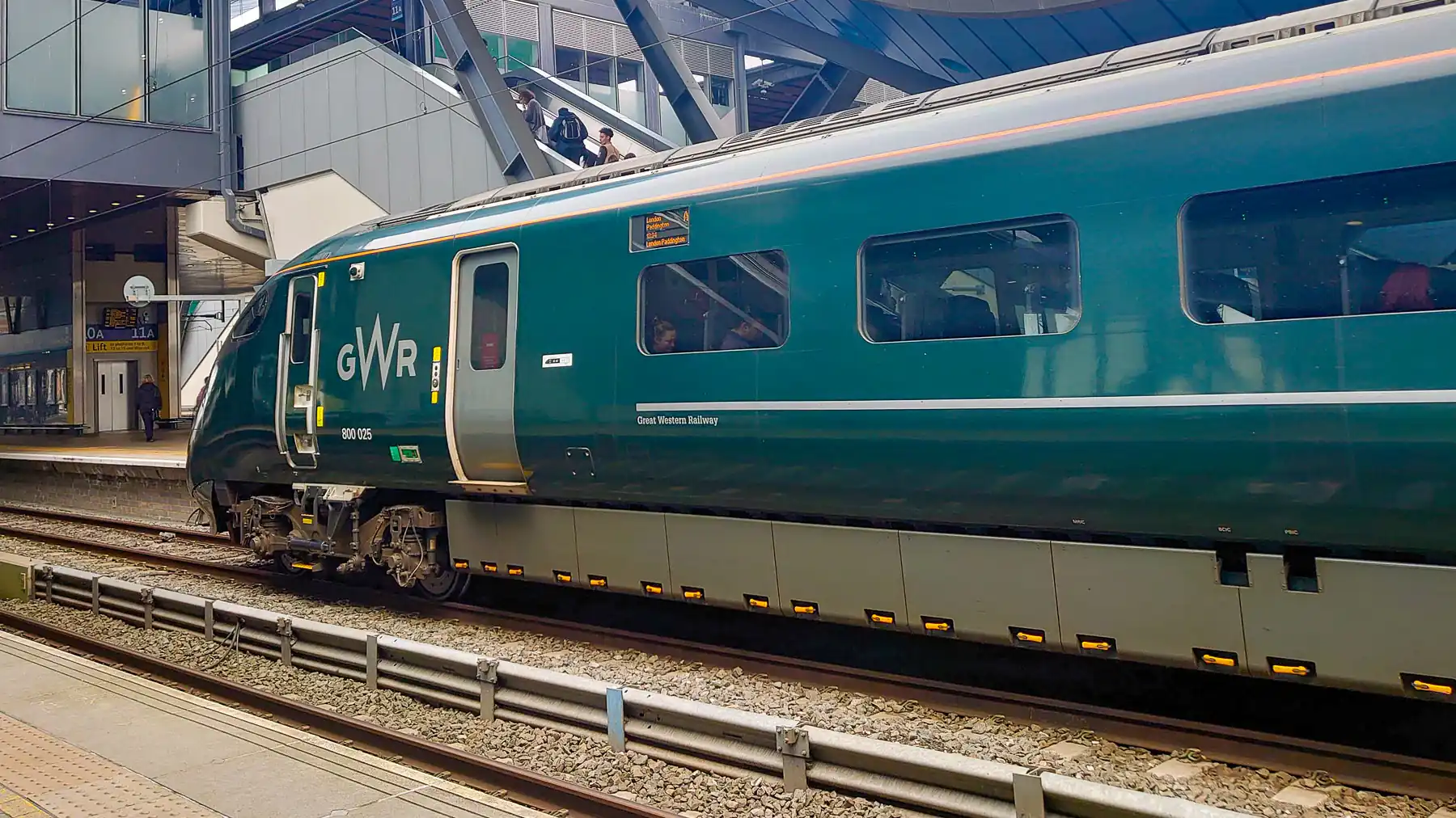 A dark green Great Western Railway train waits on a station platform